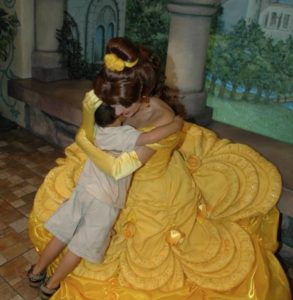 a woman in a yellow dress hugging a boy
