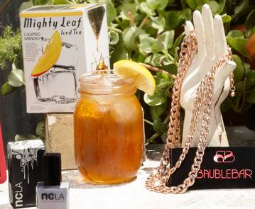 a glass jar with a lemon slice next to a necklace and a box of nail polish