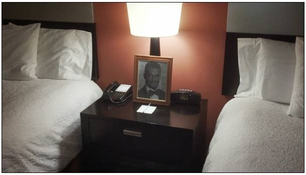 a picture of a man on a night stand next to a bed
