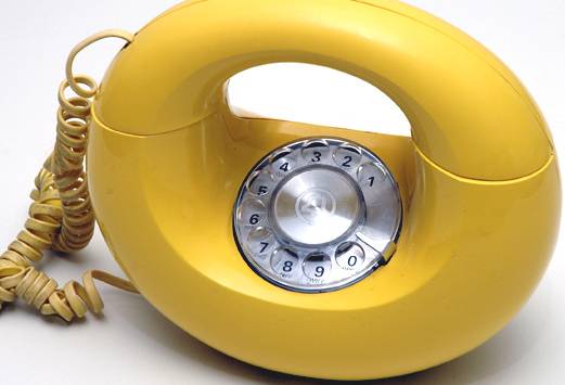 a yellow rotary phone with a cord