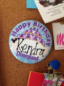 a pin with a birthday hat and other items on a cork board