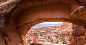 a rock arch with a view of the valley