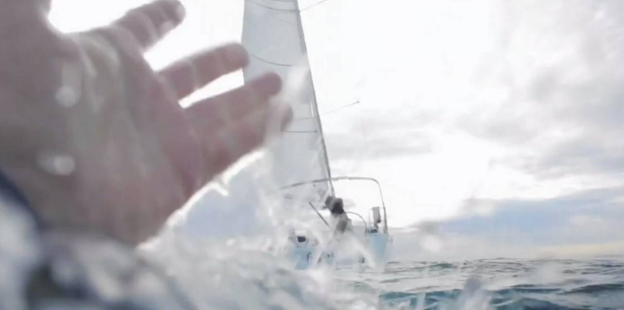 a hand reaching out to the side of a sailboat