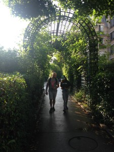 a couple of people walking under a green arch