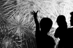 a silhouette of a couple of people with fireworks in the background