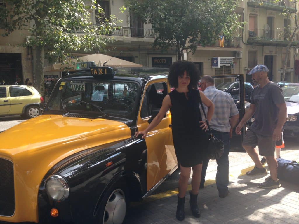 a woman standing next to a yellow and black taxi