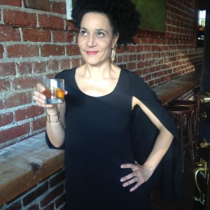 a woman in a black dress holding a glass of whiskey