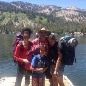 a group of people standing on a dock with a lake and mountains in the background