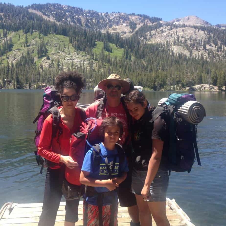a group of people standing on a dock with a lake and mountains in the background